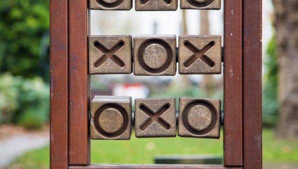 A vertical shot of wooden tic-tac-toe in the park with a blurred background